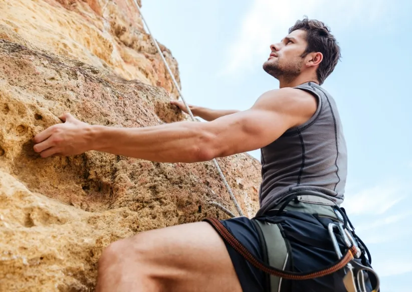 young sportsman climbing up a rock cliff utc