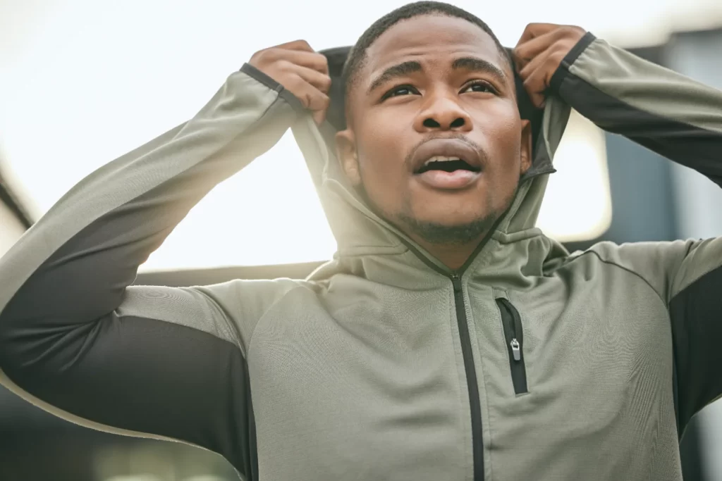 young man adjusting hoodie in urban setting utc