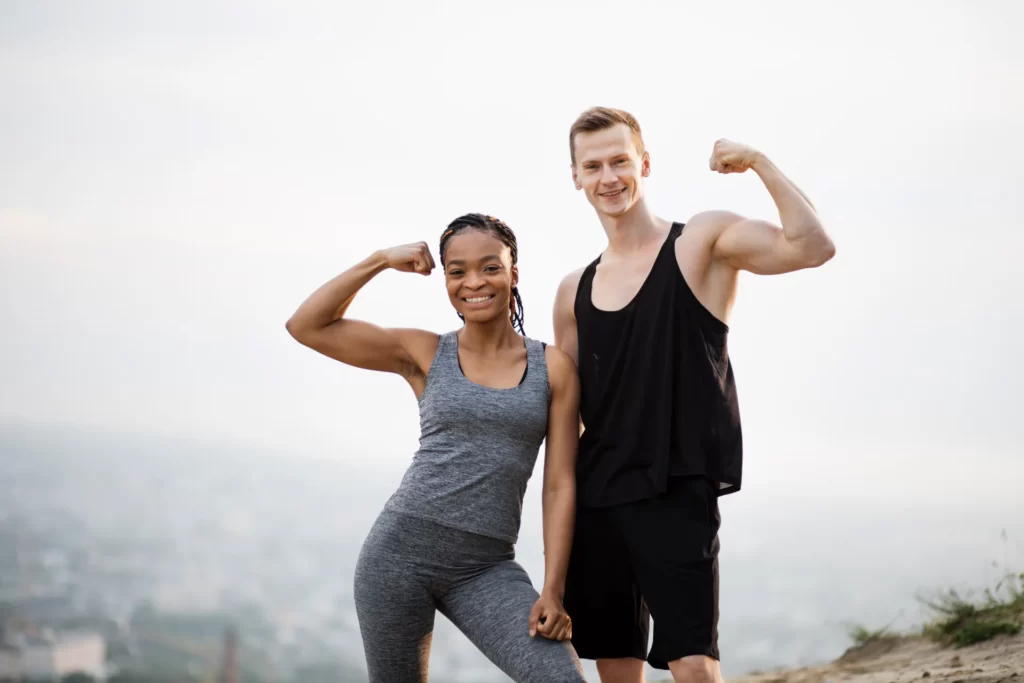 athletic man and woman flexing biceps outdoors utc